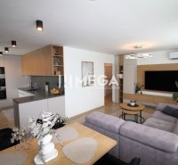 REZERVOVANÝ PRÉMIOVÝ 3-IZBOVÝ BYT S VÝHĽADOM 77 m² v Humennom - Obývacia izba s kuchyňou, sivá sedacia súprava, podlaha s dreveným dekorom, 3-izbový byt.