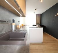 REZERVOVANÝ PRÉMIOVÝ 3-IZBOVÝ BYT S VÝHĽADOM 77 m² v Humennom - Kuchyňa v 3-izbovom byte s podlahou s dreveným dekorom a tmavou stenou.