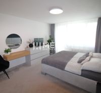 REZERVOVANÝ PRÉMIOVÝ 3-IZBOVÝ BYT S VÝHĽADOM 77 m² v Humennom - Svetlá spálňa s posteľou a komodou v 3-izbovom byte, doplnená rastlinou a kreslom.
