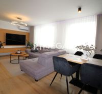 REZERVOVANÝ PRÉMIOVÝ 3-IZBOVÝ BYT S VÝHĽADOM 77 m² v Humennom - Obývacia izba v 3-izbovom byte s podlahou s dreveným dekorom a veľkou sedačkou.