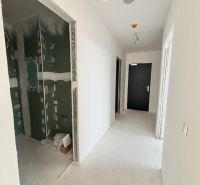NA PREDAJ | 3izb. veľkometrážny ateliér | Prístavná ulica - Chodba v 3-izbovom byte, svetlé steny, čierne dvere, nedokončená miestnosť vlavo.