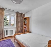 Výnimočný 6-izbový rodinný dom  v Seredi na Rovnej ulici - Spálňa s posteľou, drevenými skriňami a podlahou s dreveným dekorom v rodinnom dome.