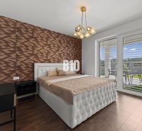 Moderný 4i dom v RED OAK, Lužianky | Kompletné zariadenie! - Spálňa s podlahou s dreveným dekorom, prešívaným posteľným čelom a výhľadom na terasu.