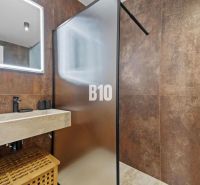 Moderný 4i dom v RED OAK, Lužianky | Kompletné zariadenie! - Kúpeľňa s priesvitnou sprchovou stenou, kamenným umývadlom a dekoratívnym osvetlením.