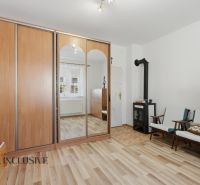 Na predaj 5-izb. dvojgen. rodinný dom, Dúbravica - Izba v rodinnom dome s kozubom, skriňou a podlahou s dreveným dekorom.
