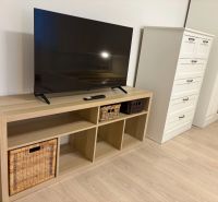 Pekný prenájom 1 izbový byt, Trenčianska ulica, Bratislava II Ružinov  - TV na poličke s košíkmi, vedľa komody a skrine, podlaha s dreveným dekorom.