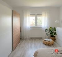 Priestranný 4i byt s parkovacím miestom 20min od Bratislavy - Svetlá spálňa v 4-izbovom byte s minimalistickým nábytkom a podlahou s dreveným dekorom.