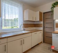 Priestranný 4i byt s parkovacím miestom 20min od Bratislavy - Kuchyňa v 4-izbovom byte s podlahou s dreveným dekorom a výhľadom do záhrady.