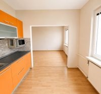 Predaj! slnečný 3-izbový byt s loggiou 74 m² Podbreziny - LM - Kuchyňa a obývacia izba s oranžovou linkou v 3-izbovom byte, podlaha s dreveným dekorom.