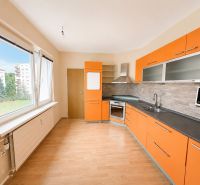 Predaj! slnečný 3-izbový byt s loggiou 74 m² Podbreziny - LM - Kuchyňa v 3-izbovom byte s oranžovými skrinkami a podlahou s dreveným dekorom.