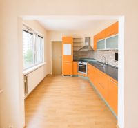 Predaj! slnečný 3-izbový byt s loggiou 74 m² Podbreziny - LM - Kuchyňa so vstavanými spotrebičmi, výrazným oranžovým nábytkom a podlahou s dreveným dekorom v 3-izbovom byte.