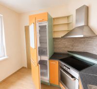 Predaj! slnečný 3-izbový byt s loggiou 74 m² Podbreziny - LM - Kuchyňa v 3-izbovom byte s podlahou s dreveným dekorom a farebnými skrinkami.