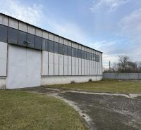 Sklad. priestory 200m2 - 1000m2, spevnené plochy do 6000m2 v areáli. - Skladová hala v Bratislave-Rači s oceľovou konštrukciou a zeleným trávnikom v popredí.