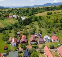 | Výnimočný rodinný dom s pozemkom 1516 m2 Nízke Tatry - Pohľad na rodinné domy v HorneJ Lehote s kopcovitou krajinou v pozadí.