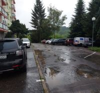 Predaj investičného pozemku. Podborová - Parkovisko na Ružovej ulici v meste Zvolen, obklopené zeleňou a autami.