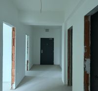 Nové skolaudované byty a apartmány vo Vajnoroch. - Svetlá chodba v 2-izbovom byte s bielymi stenami a betónovou podlahou.