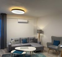 Nové skolaudované byty a apartmány v projekte Diamant. - Obývacia izba s pohovkou, kreslom a stolíkom v 2-izbovom byte s dekorom podlahy.