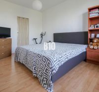 2-izbový byt s balkónom a klimatizáciou | Štúrova, Nitra - Spálňa v 2-izbovom byte s podlahou s dreveným dekorom, posteľou a policou.