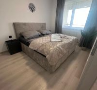 Prenájom 2 izbového bytu ARBORIA Trnava - Spálňa v 2-izbovom byte s posteľou a podlahou s dreveným dekorom.