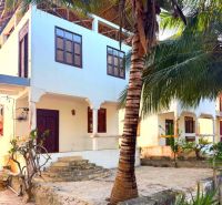 SAMOSTATNE STOJACA VILA MAPUMZIKO S 2 IZBAMI NA ZANZIBARE  - Rodinný dom v Fumba Town obklopený palmou a tropickou vegetáciou, schody vedúce na verandu.