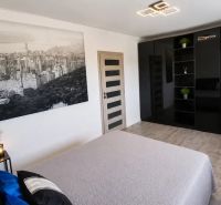ZARIADENÁ NOVOSTAVBA 5 MINÚT OD TRNAVY - Spálňa s čiernou šatníkovou skriňou, veľkou fotografiou a izbovými rastlinami.