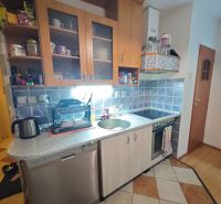 PREDAJ 2-izbový byt Harmanec 56 m2 s balkónom  - Kuchyňa v 2-izbovom byte s modrými kachličkami a podlahou s dreveným dekorom.