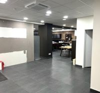 PRENÁJOM: Obchodné priestory 238m2, parkovanie, Ružinov - Obchodné priestory s keramickou podlahou, stropnými svetlami a sedením v pozadí.