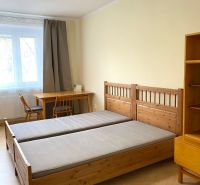 Prenájom 2-izbového bytu, Martin - centrum - Spálňa s drevenými posteľami, stolom a podlahou s dreveným dekorom v 3-izbovom byte.