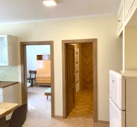 Prenájom 2-izbového bytu, Martin - centrum - Interiér 3-izbového bytu s podlahou s dreveným dekorom, stoličkami a vstavanou skriňou.