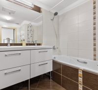 Apartmán vhodný na Airbnb aj rodinné bývanie | Vienna Gate - Kúpeľňa s vaňou v 3-izbovom byte, biele skrinky, dlažba a sprchový záves.