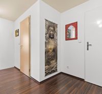 Apartmán vhodný na Airbnb aj rodinné bývanie | Vienna Gate - Vstupná chodba v 3-izbovom byte s podlahou s dreveným dekorom, zrkadlom a budhistickým motívom.
