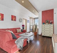 Apartmán vhodný na Airbnb aj rodinné bývanie | Vienna Gate - Obývacia izba s červenou pohovkou a podlahou s dreveným dekorom v 3-izbovom byte.