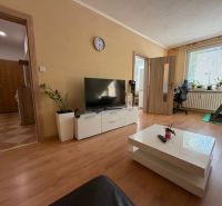 3 izbový byt s balkónom Topoľčany  - Obývačka v 3-izbovom byte s podlahou s dreveným dekorom, televíziou a bežeckým pásom.