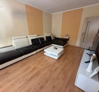3 izbový byt s balkónom Topoľčany  - Obývacia izba s pohovkou, televíziou a podlahou s dreveným dekorom v 3-izbovom byte.
