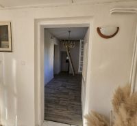 EXKLUZÍVNE NA PREDAJ 2-izbový rodinný dom v širšom centre Nitry s pote - Obývacia izba s televíziou, skriňou, oknom a podlahou s dreveným dekorom v rodinnom dome.