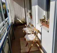 Prenájom 1 izbový byt, ulica Donnerova, Bratislava IV. Karlova Ves - Balkón v 1-izbovom byte s kvetmi, kreslami a stolíkom na Donnerovej ulici.