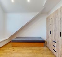 Prémiový podkrovný mezonet v centre Michaloviec | 109,3 m² |  - Spálňa v 4-izbovom byte s podlahou s dreveným dekorom a úložným priestorom.