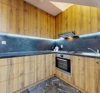Prémiový podkrovný mezonet v centre Michaloviec | 109,3 m² |  - Kuchyňa so skriňami s dreveným dekorom a spotrebičmi v 4-izbovom byte.