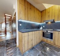 Prémiový podkrovný mezonet v centre Michaloviec | 109,3 m² |  - Kuchyňa v 4-izbovom byte s podlahou s dreveným dekorom a točitým schodiskom.