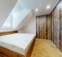Prémiový podkrovný mezonet v centre Michaloviec | 109,3 m² |  - Spálňa so šikmým stropom, vstavanou skriňou a podlahou s dreveným dekorom v 4-izbovom byte.