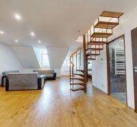 Prémiový podkrovný mezonet v centre Michaloviec | 109,3 m² |  - Podkrovná obývačka v 4-izbovom byte, podlaha s dreveným dekorom, točité schodisko.