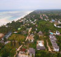 OFF-PLAN VILA MAPUMZIKO S 1 SPALŇOU NA ZANZIBARE  - Pohľad na pobrežie a rodinné domy vo Fumba Town, obklopené tropickou prírodou.