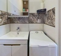 Garsónka po kompletnej rekonštrukcii v širšom centre mesta - Kúpeľňa v Rekreačnom apartmáne s práčkou a vzorovanými obkladmi na stenách.