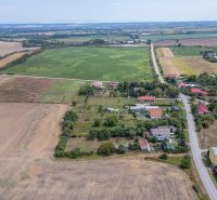 PREDAJ, Stavebný pozemok Sečovce - časť Albinov, intravilan  - Letecký pohľad na pozemky pre bývanie v Sečovciach, obklopené poľom a dedinskou zástavbou.