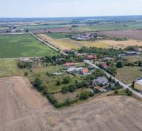 PREDAJ, Stavebný pozemok Sečovce - časť Albinov, intravilan  - Letecký pohľad na pozemky určené na bývanie v Sečovciach, obklopené poliami a domami.