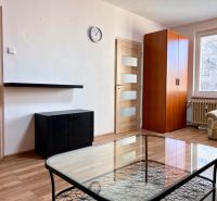 Na predaj 2 izbový byt, 47 m2, Bratislava, Nové Mesto, Piešťanská ul. - Obývacia izba v 2-izbovom byte s podlahou s dreveným dekorom, pohovkou a skriňou.