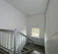 Na predaj 2 izbový byt 54 m2 po rekonštrukcii + záhrada, obec Telince - Schodisko s oknom v 2-izbovom byte, steny sú biele s kovovým zábradlím.