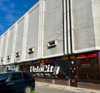 Nadštandardne veľká garáž na ul. Medveďovej, Petržalka - Budova s obchodnými priestormi a parkujúcimi autami na Medveďovej ulici v Petržalke.