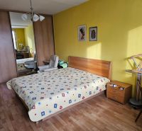 Veľký 2-izb. byt na ul. Nezábudková, Ružinov pri OC Retro - Spálňa v 2-izbovom byte s podlahou s dreveným dekorom, žltými stenami a vstavanou skriňou.