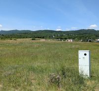 Stavebný pozemok 681 m2 v Štitároch  - Rozľahlé zelené pole s viditeľnou budovou a kopcami v Štitároch na Zamoyského, Pozemky - bývanie.